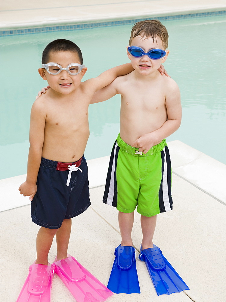 Boys in flippers posing by swimming pool