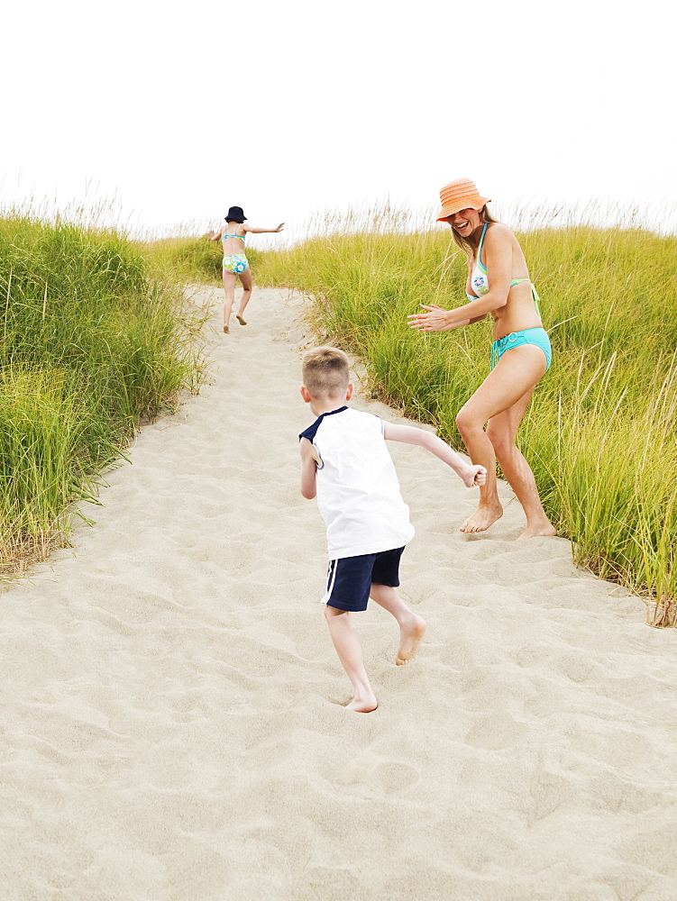 Mother running on beach with daughter and son