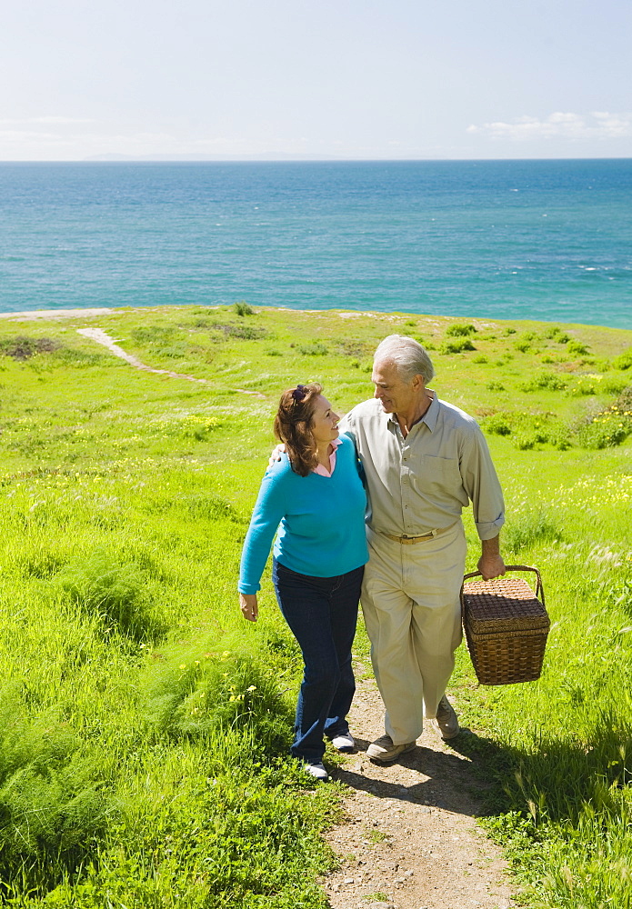 Couple carrying picnic basket to the beach