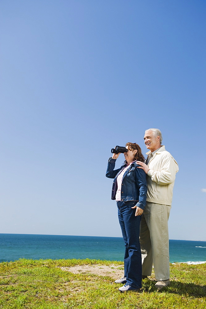 Couple looking at ocean with binoculars