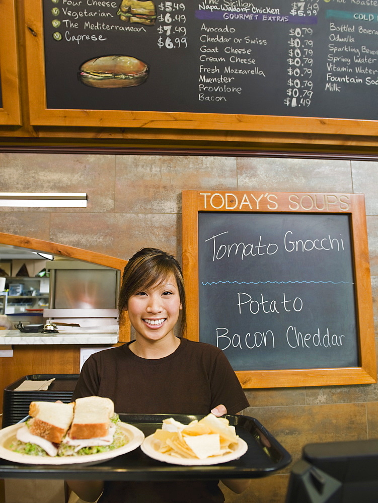 Woman holding tray of food in bakery