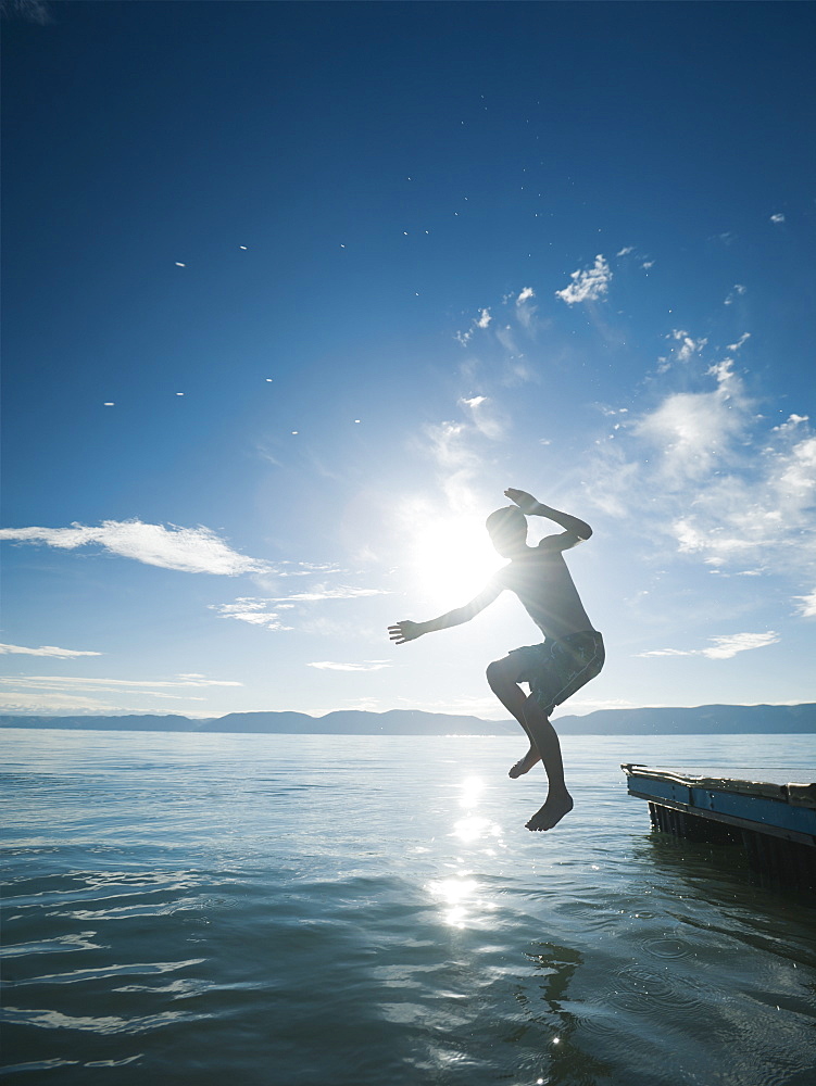 Boy (10-11) jumping from raft