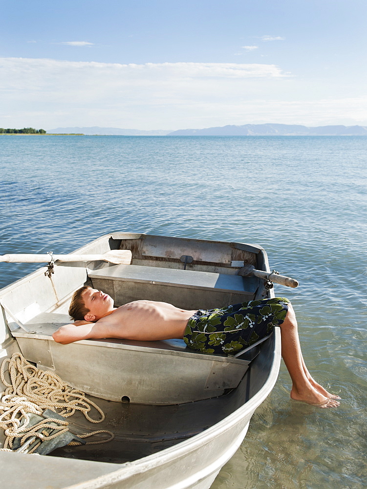 Boy (10-11) resting on boat