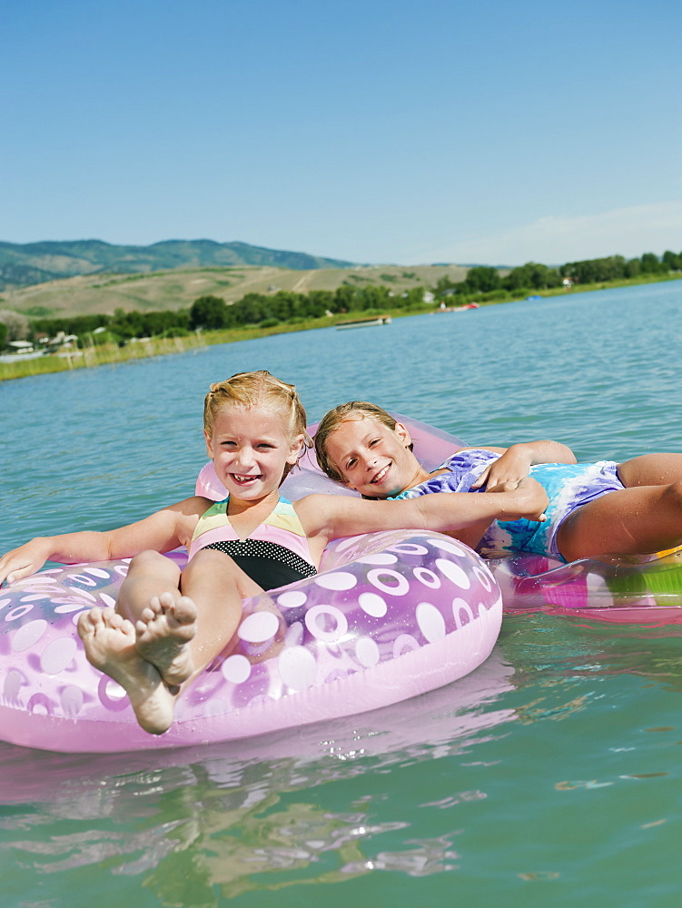 Girls (6-7,8-9) floating on inflatable toys