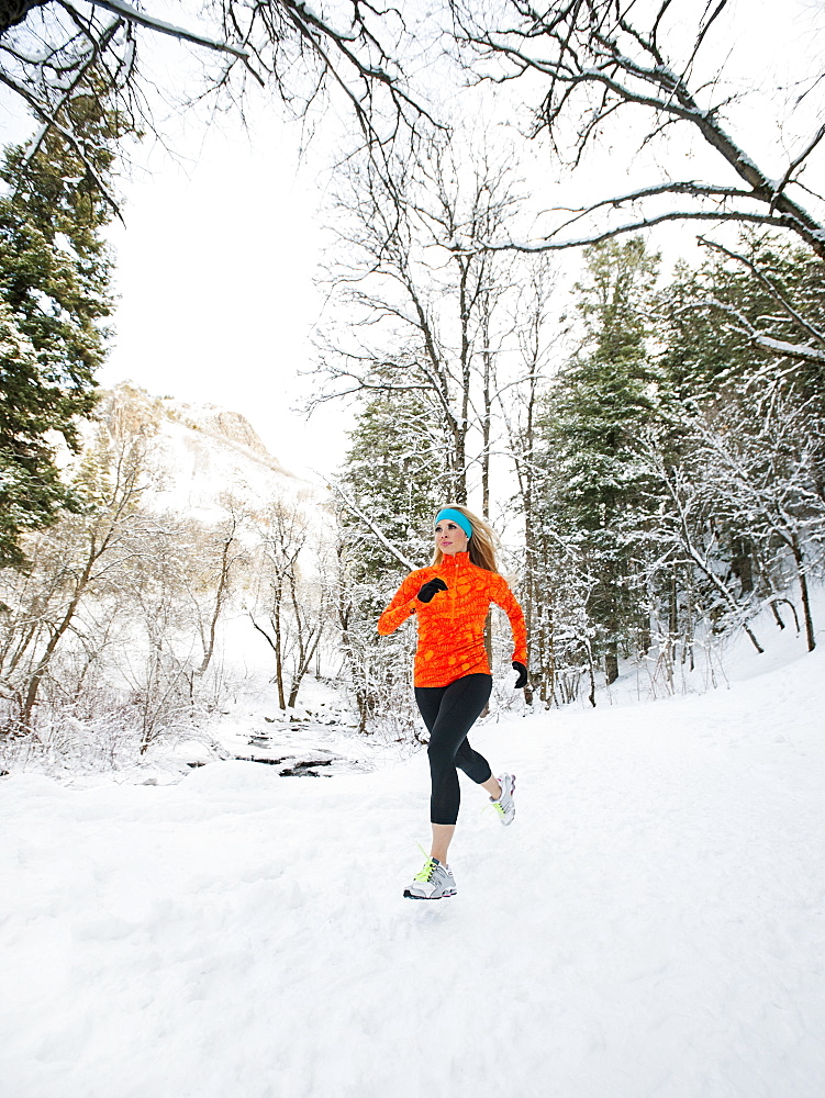 Woman jogging in winter forest, Salt Lake City, Utah USA