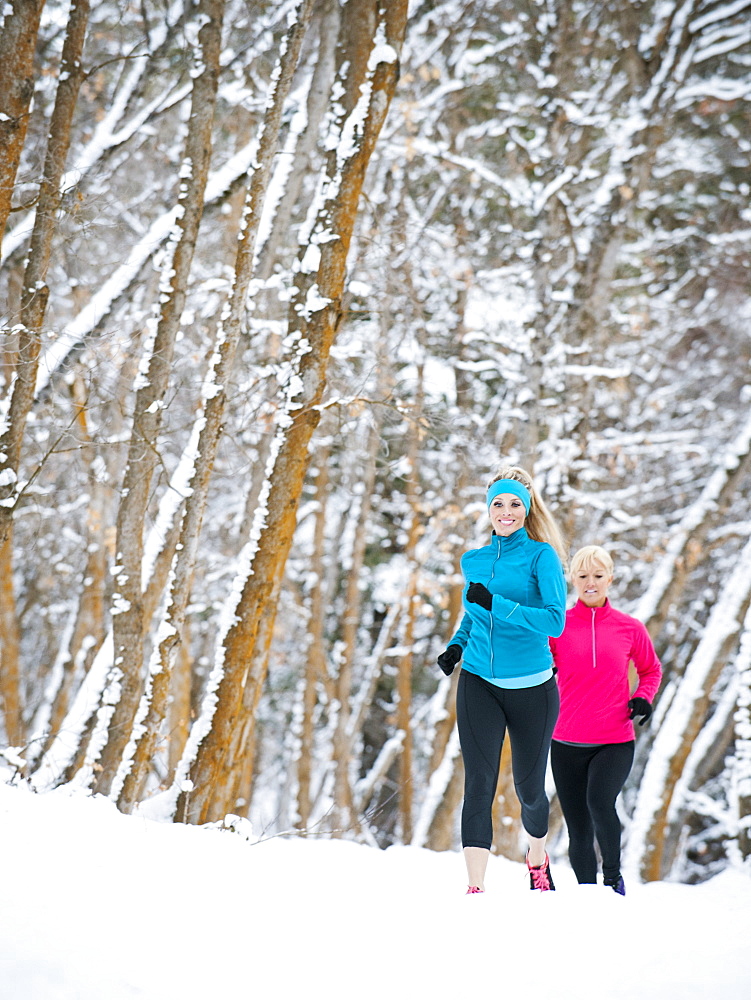 Two women jogging in winter forest, Salt Lake City, Utah USA