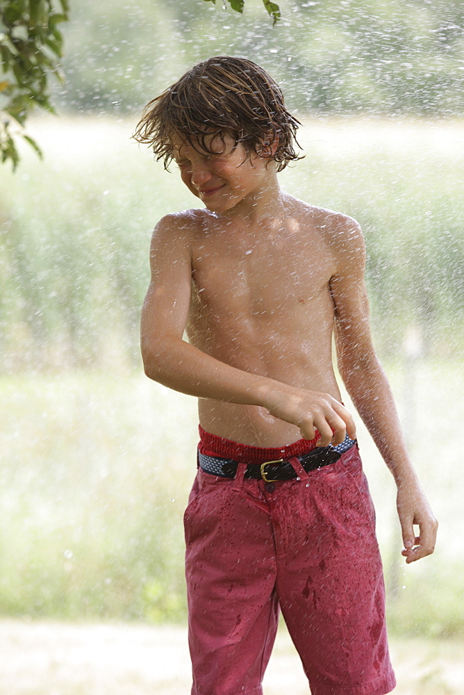 Boy (10-11) playing with splashing water, Old Wick, New Jersey