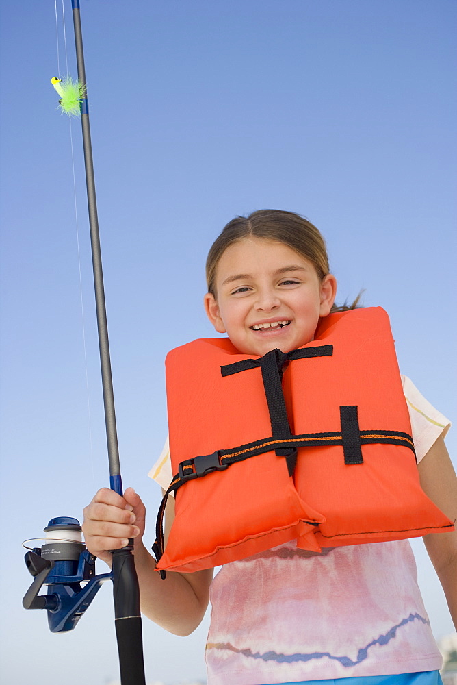 Girl in life jacket holding fishing pole