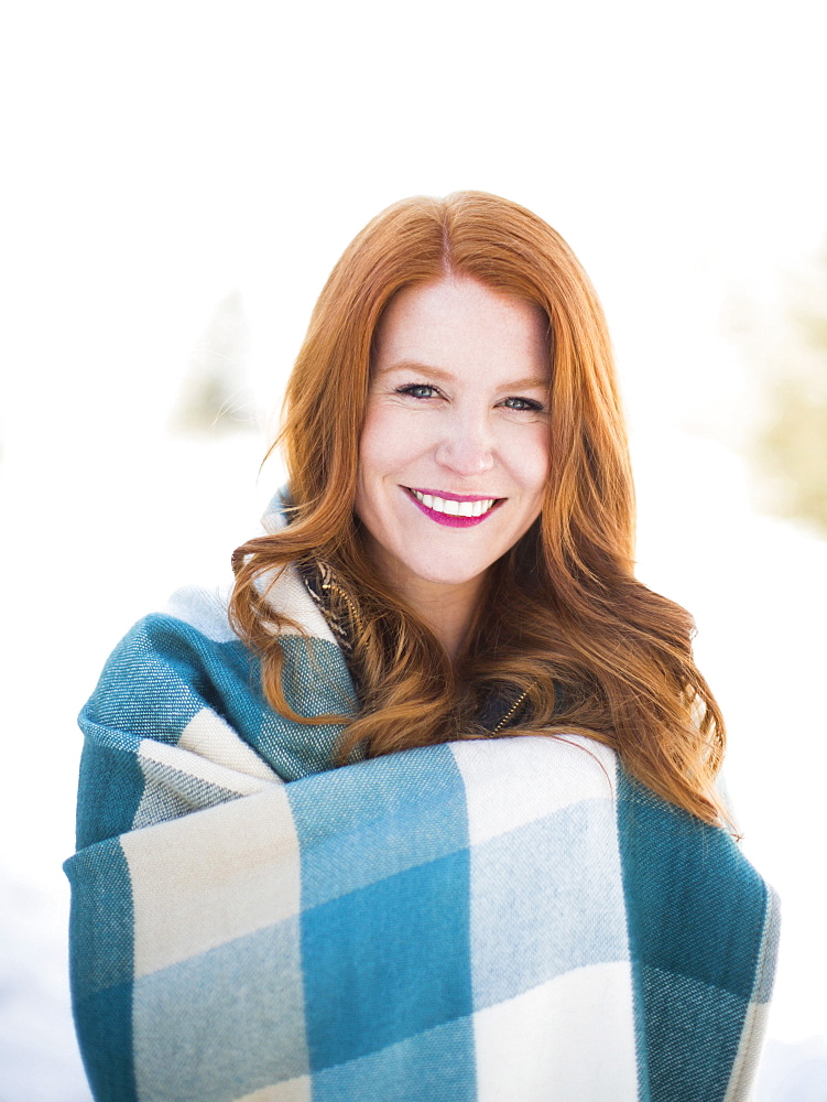 Portrait of mid adult woman wrapped in checked blanket