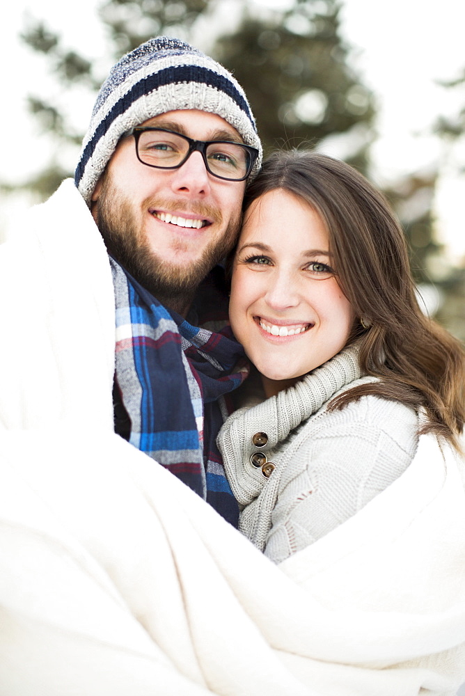 Portrait of couple wrapped in blanket smiling outdoors