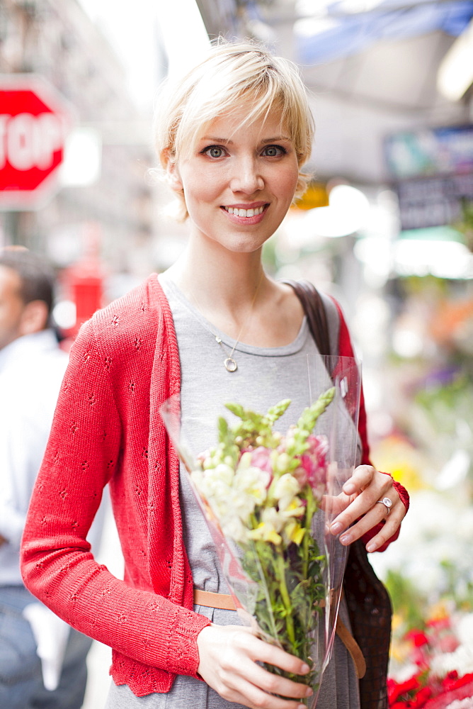 Portrait of smiling woman holding bunch of flowers, USA, New York State, New York