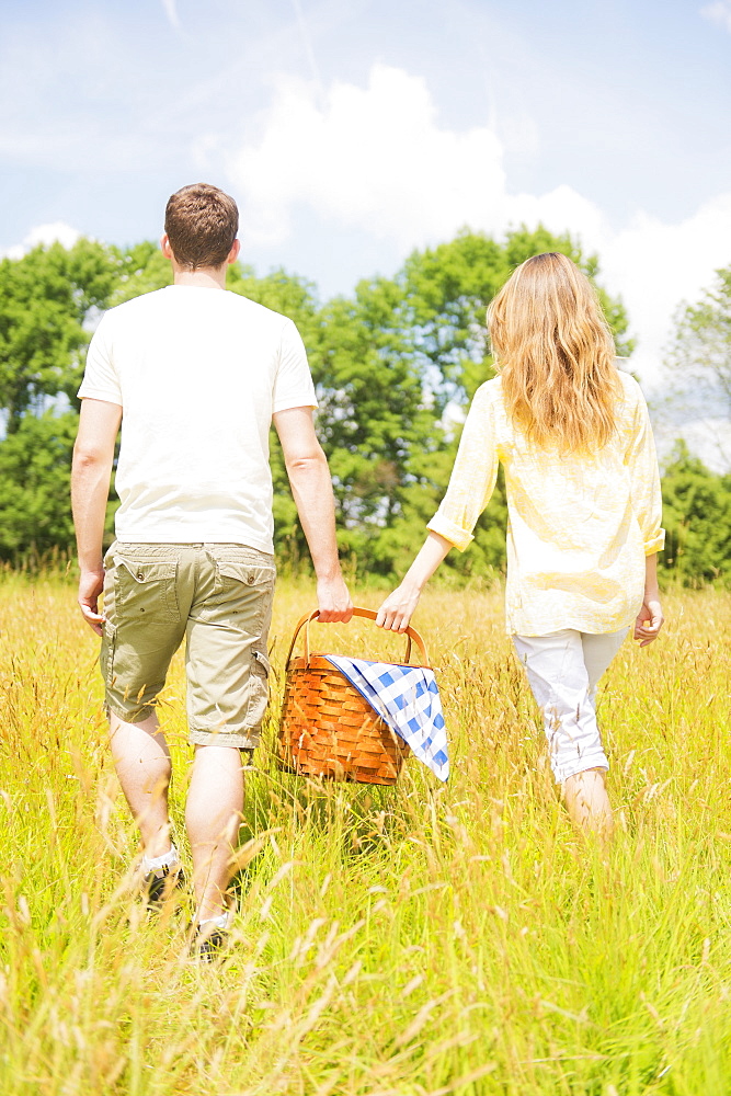 Couple walking with picnic basket on meadow, USA, New Jersey, Mendham