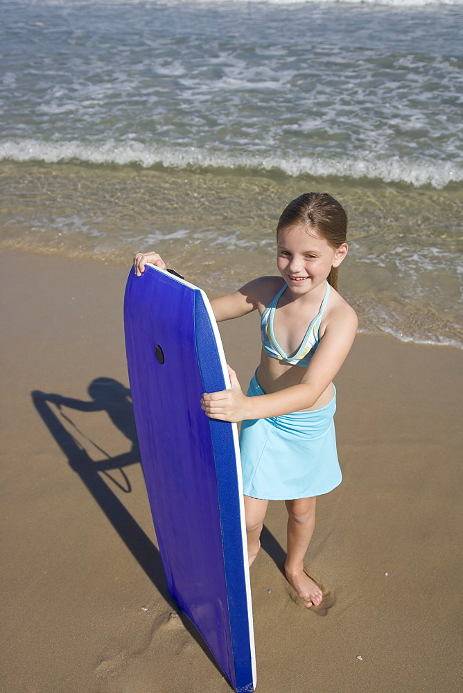 Girl holding boogie board at beach