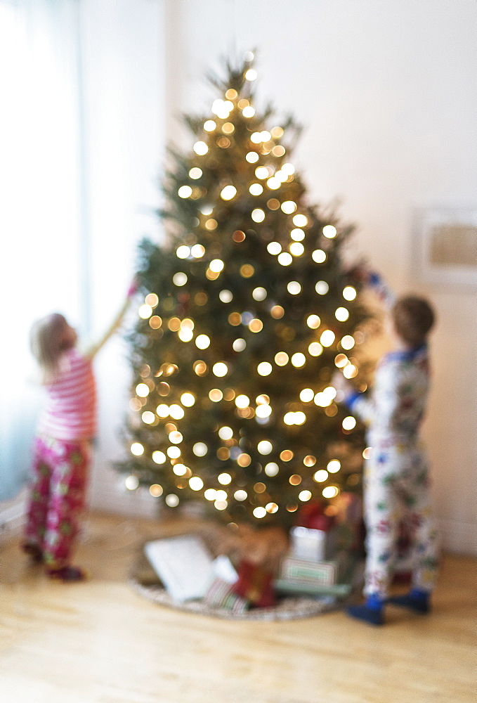 Sister and brother (4-5, 6-7) decorating christmas tree