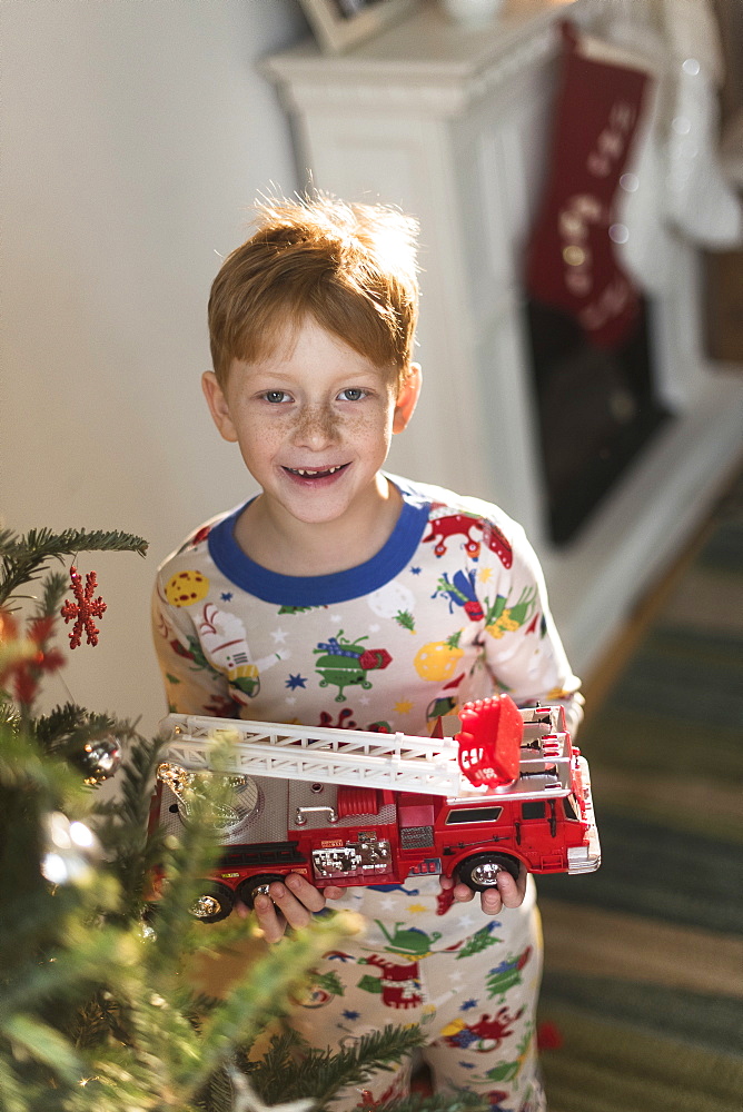 Portrait of boy (6-7) holding toy firetruck