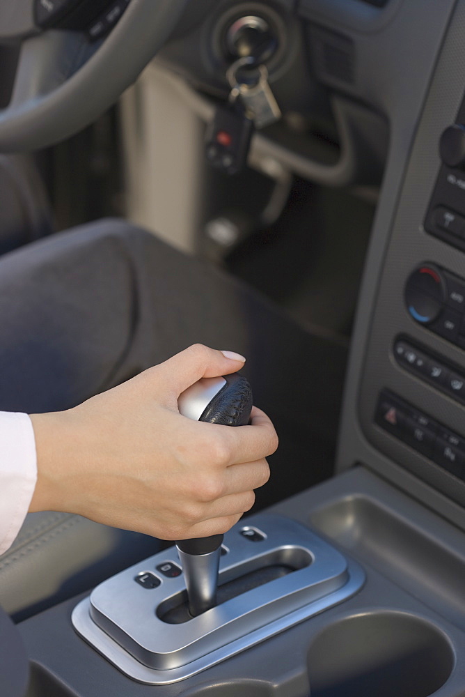 Woman with hand on automatic gearshift in car