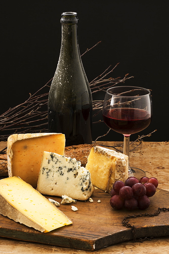 Still life with cheese and red wine on wooden table, studio shot