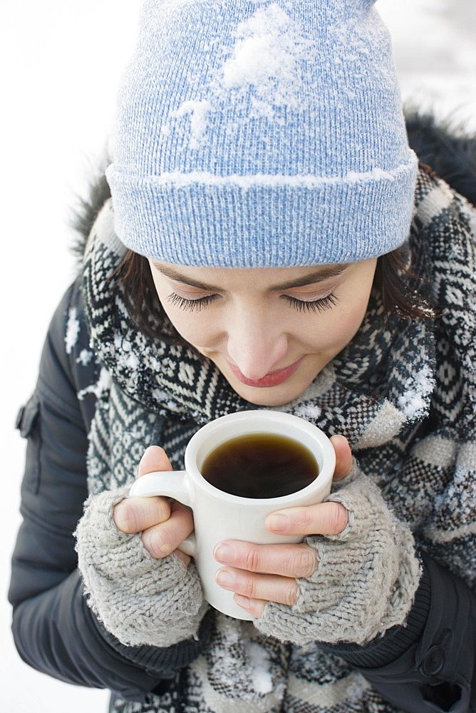 Woman with coffee mug in snow