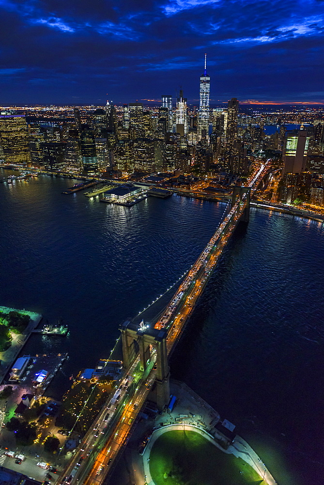 USA, New York, New York City, Manhattan, Aerial view of illuminated skyline with harbor and Brooklyn bridge at night