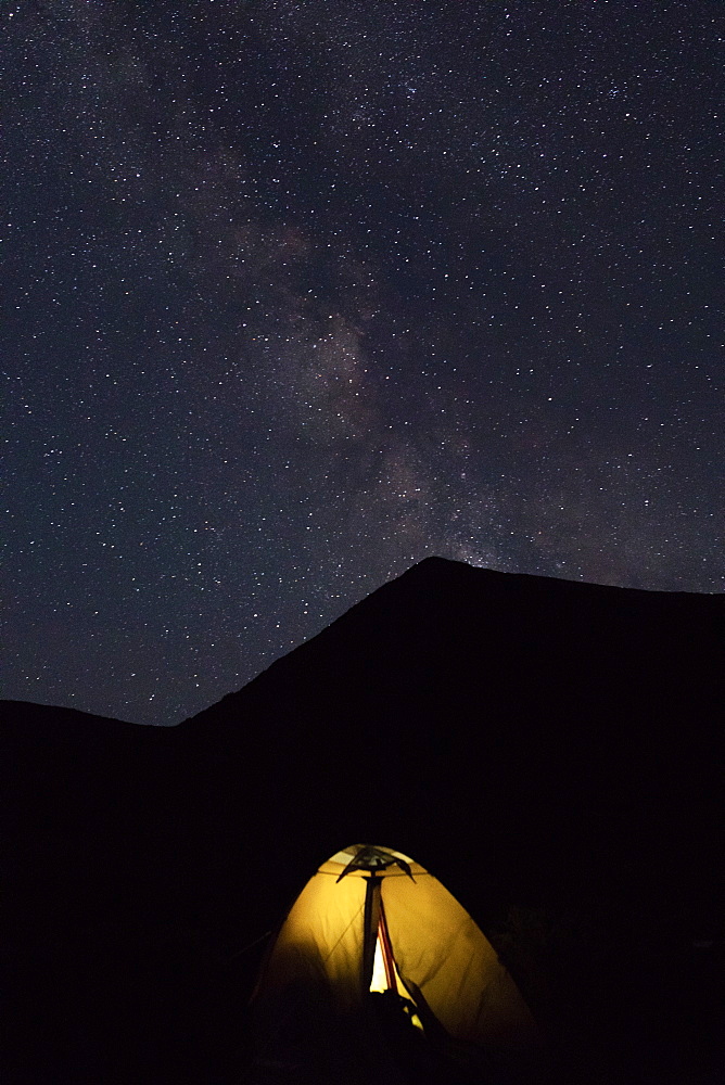 Illuminated tent by mountain at night