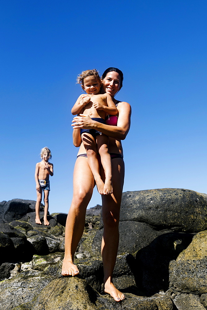 Woman with her sons on rocks at beach