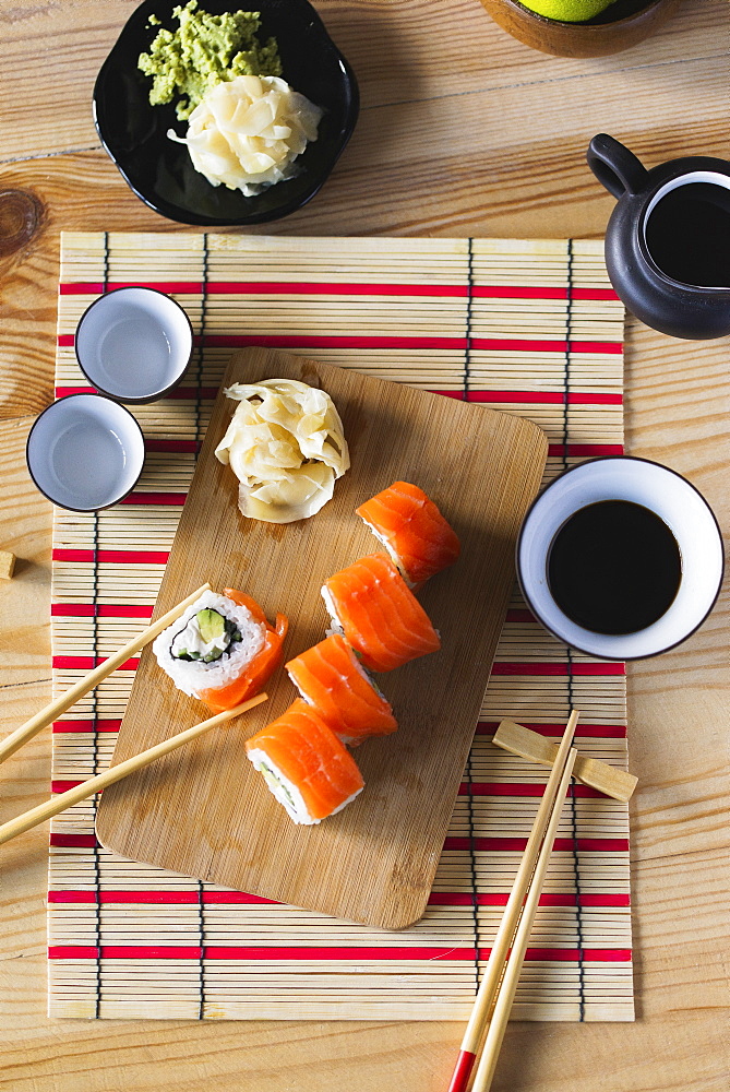 Salmon sushi on cutting board with condiments