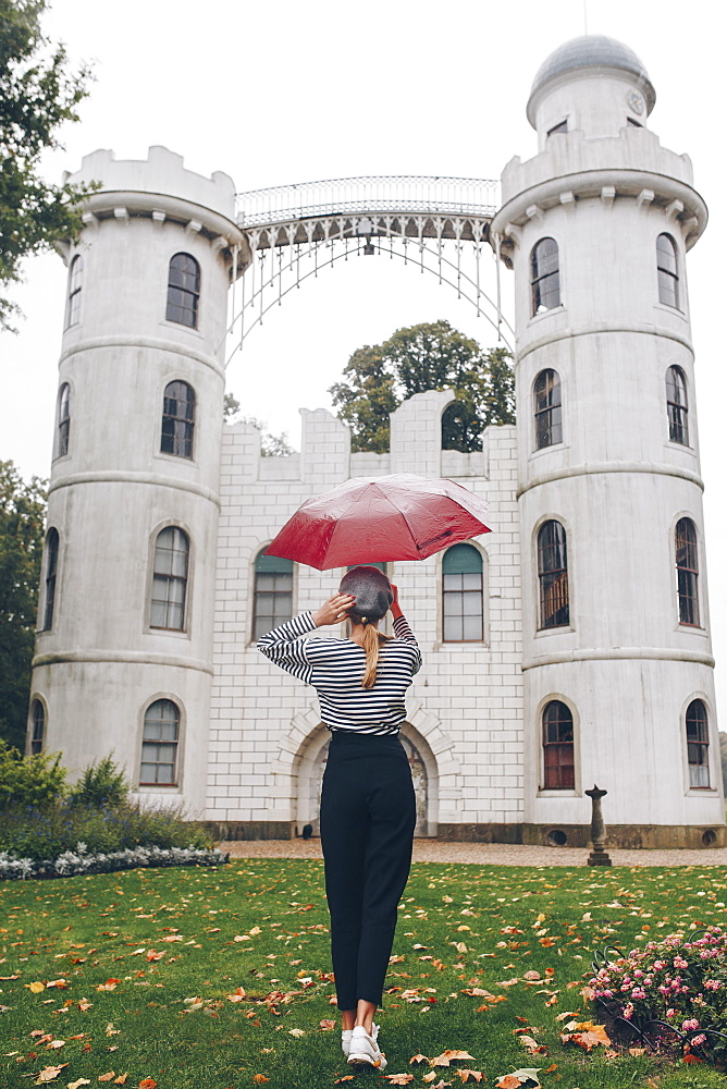 Woman holding red umbrella by Schloss Pfaueninsel in Potsdam, Germany