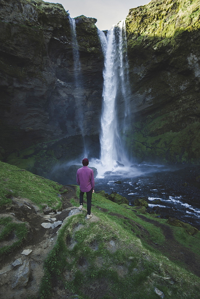 Man standing by Kvernufoss waterfall in Iceland