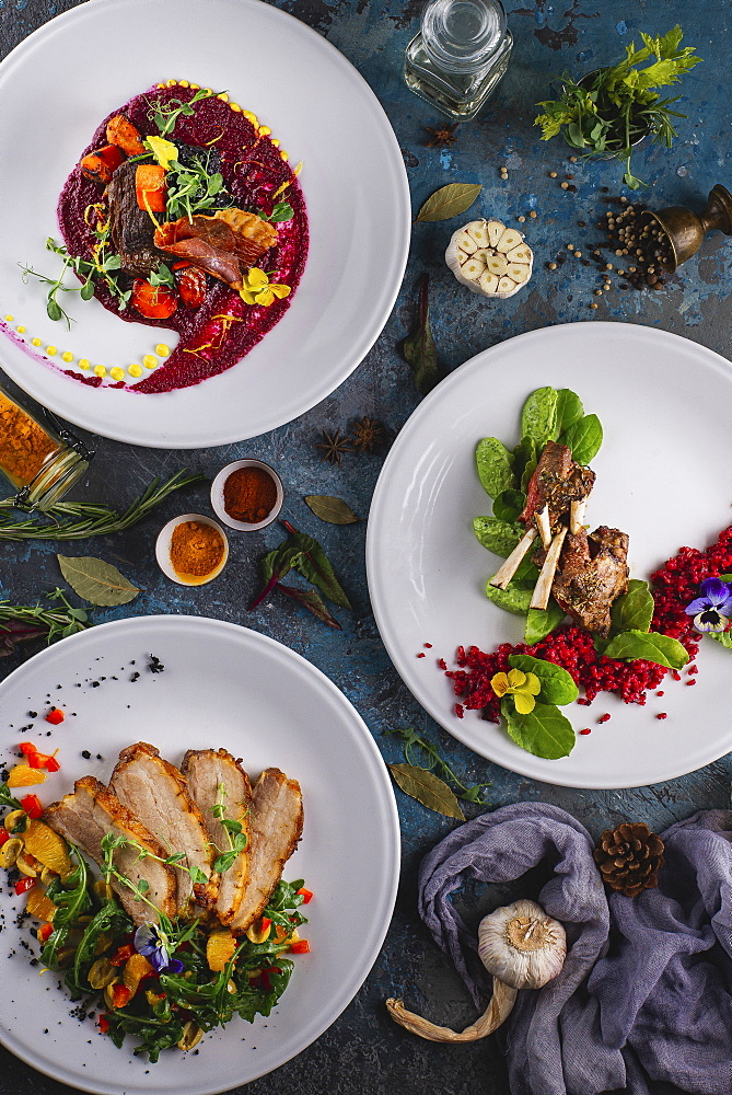 Meat dishes served on plates on dark background