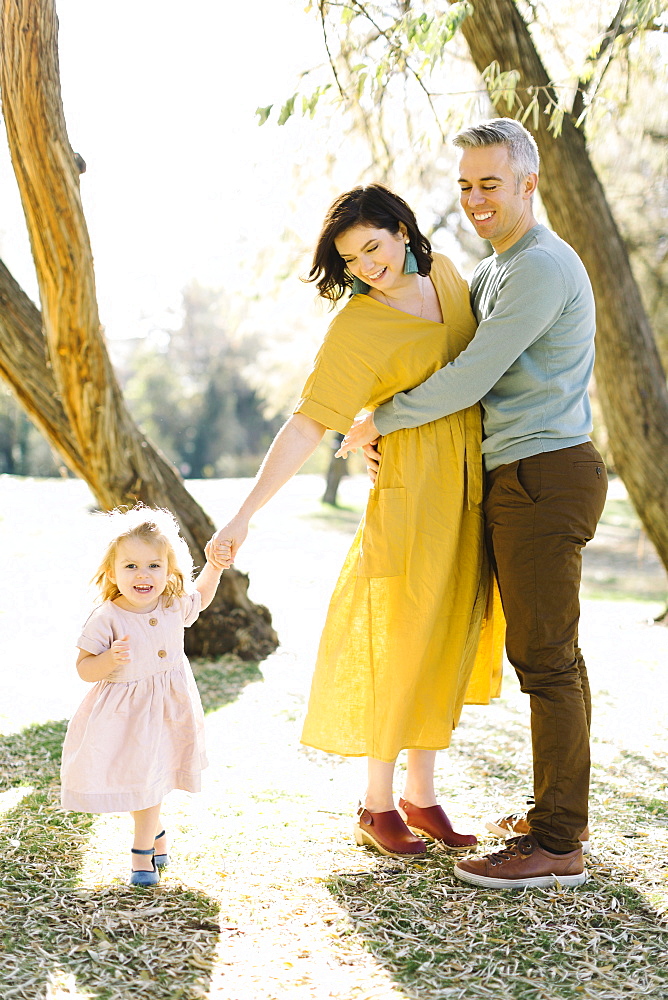 Mid adult couple holding daughter's hand in park