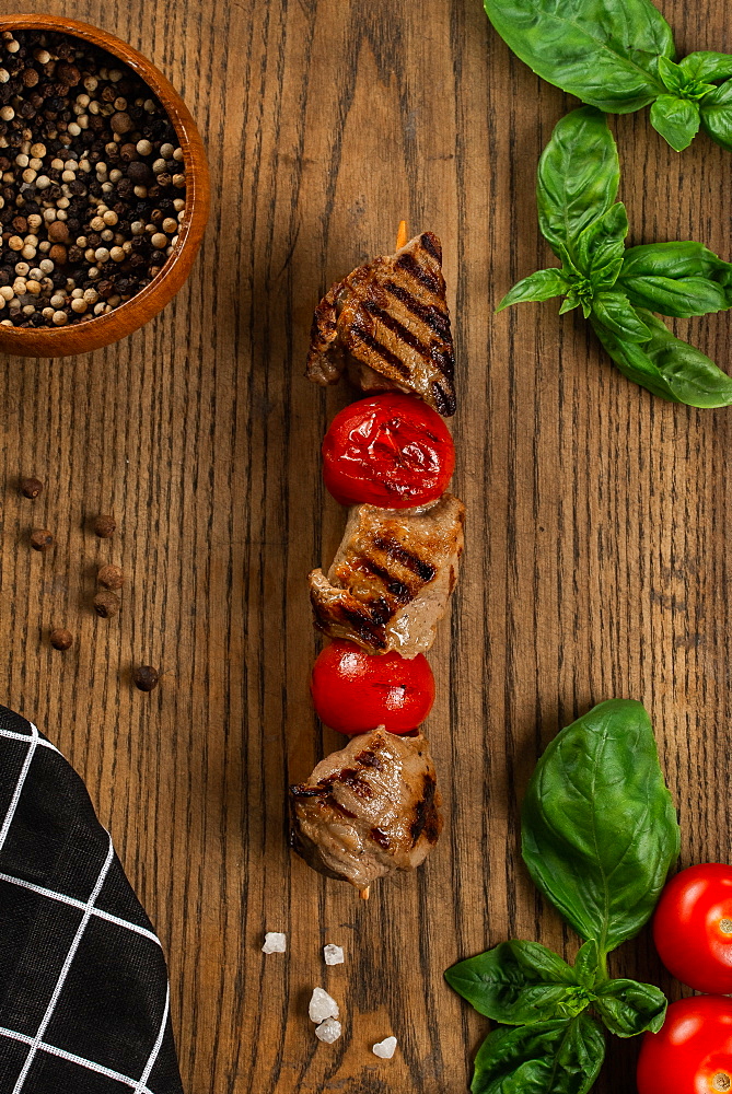 Grilled meat and tomato skewer on cutting board