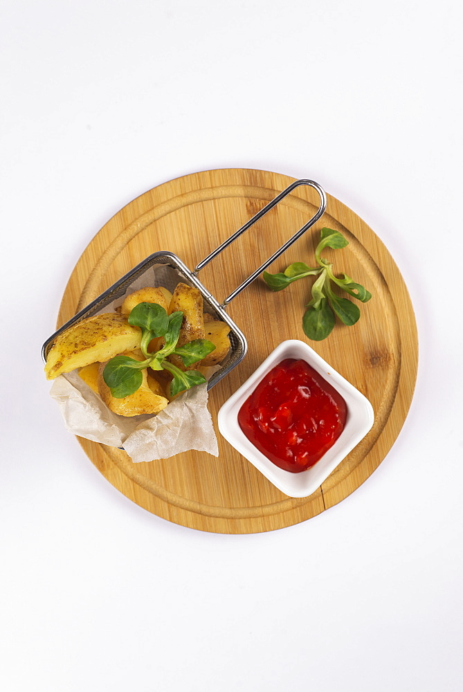 Fried potatoes with tomato sauce on cutting board