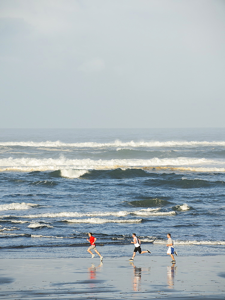 Men running on beach, Rockaway Beach, Oregon