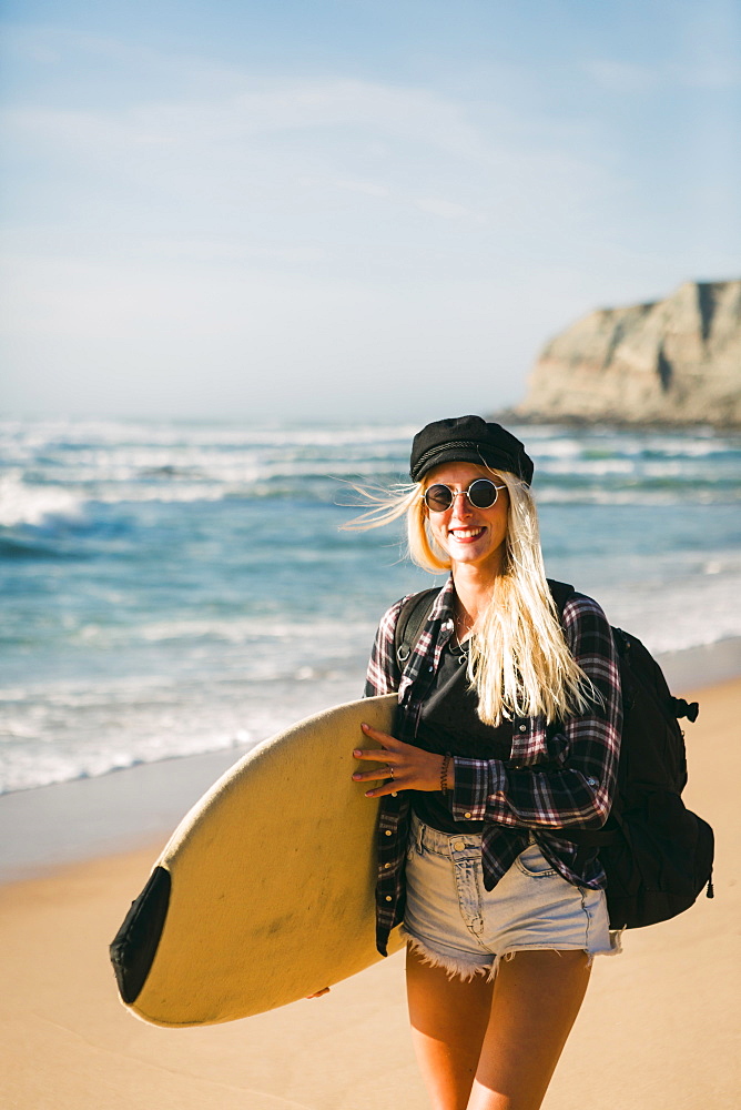 Smiling woman holding surfboard on beach