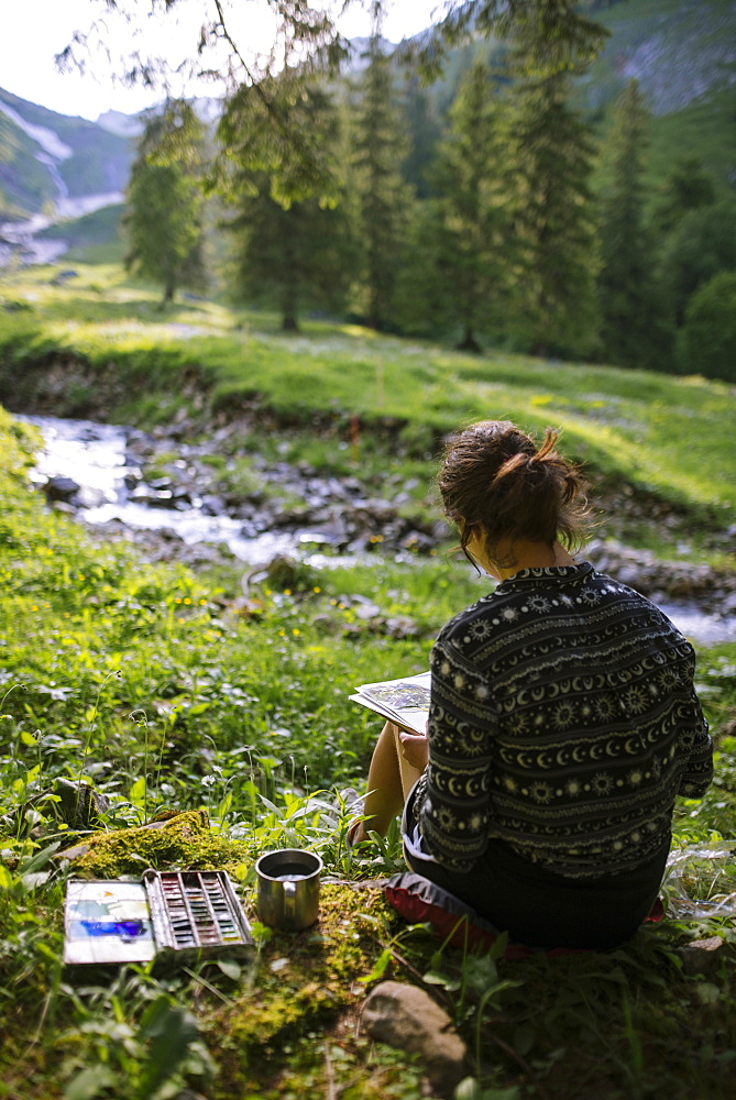 Woman painting with watercolors by river in Appenzell, Switzerland