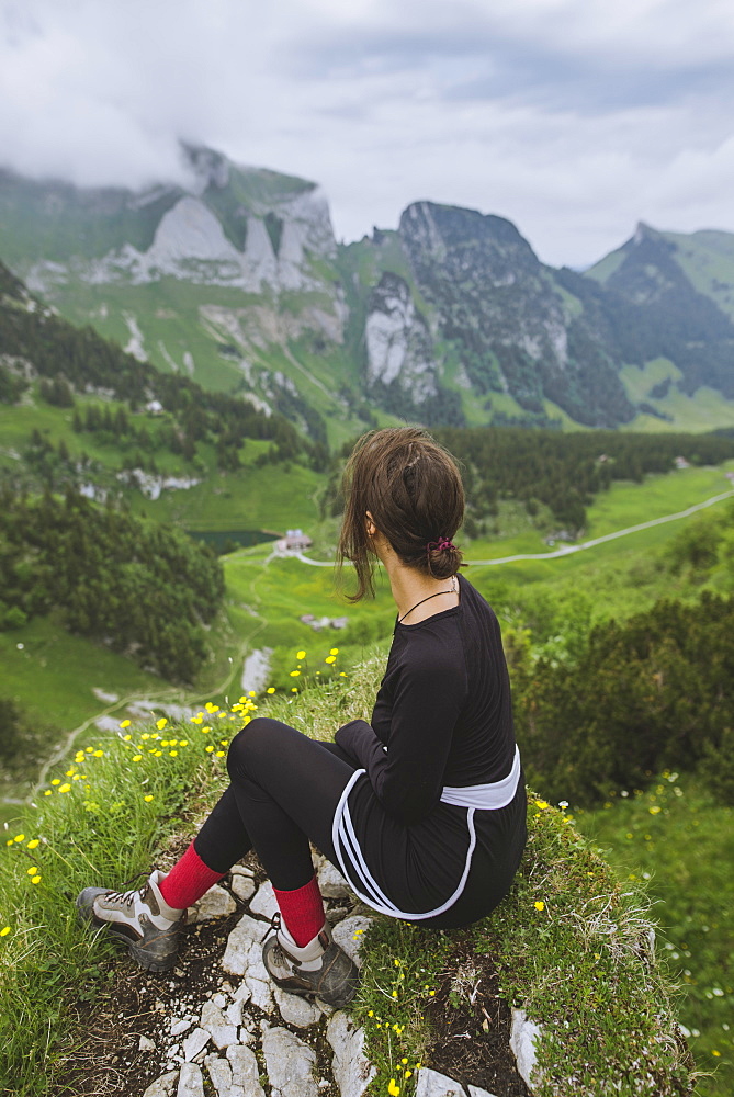 Woman sitting on rock by mountains in Appenzell, Switzerland