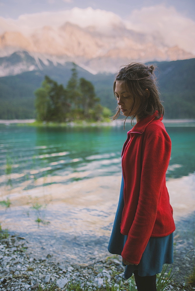 Germany, Bavaria, Eibsee, Young woman standing at shore of Eibsee lake in Bavarian Alps