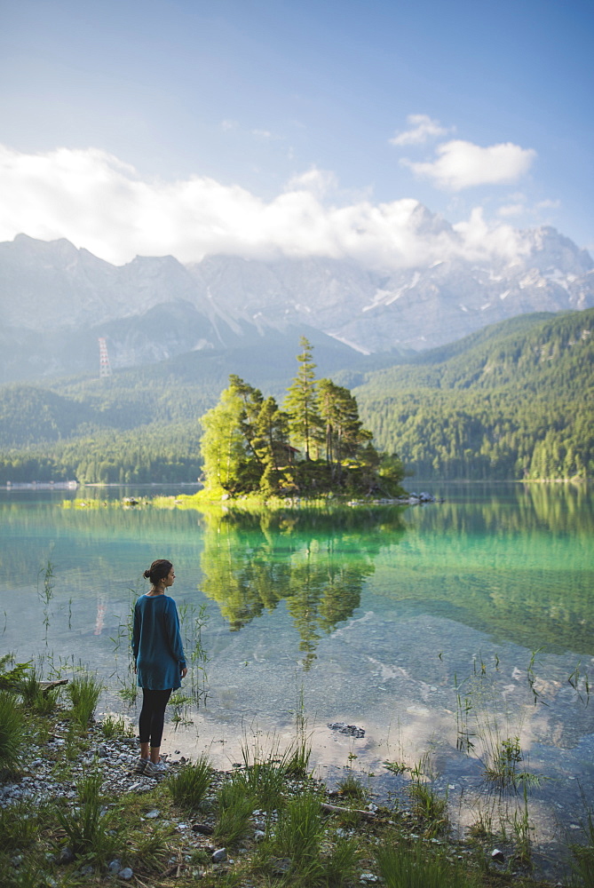 Germany, Bavaria, Eibsee, Young woman standing at shore of Eibsee lake in Bavarian Alps