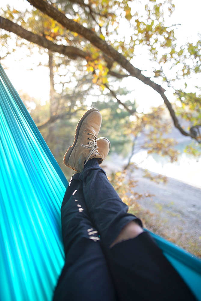 Italy, Man lying in hammock near lake