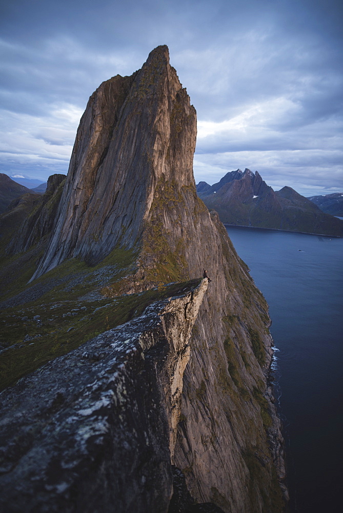 Norway, Senja, Man sitting on cliff edge near?Segla?mountain