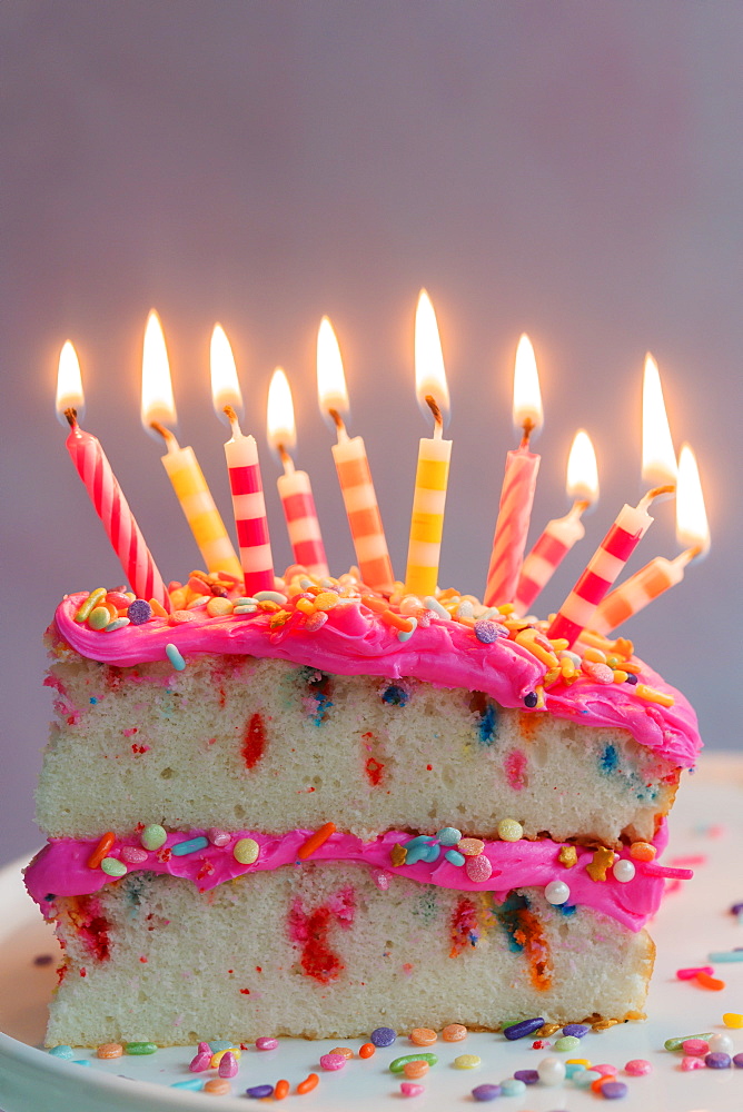 Slice of birthday cake with lit candles