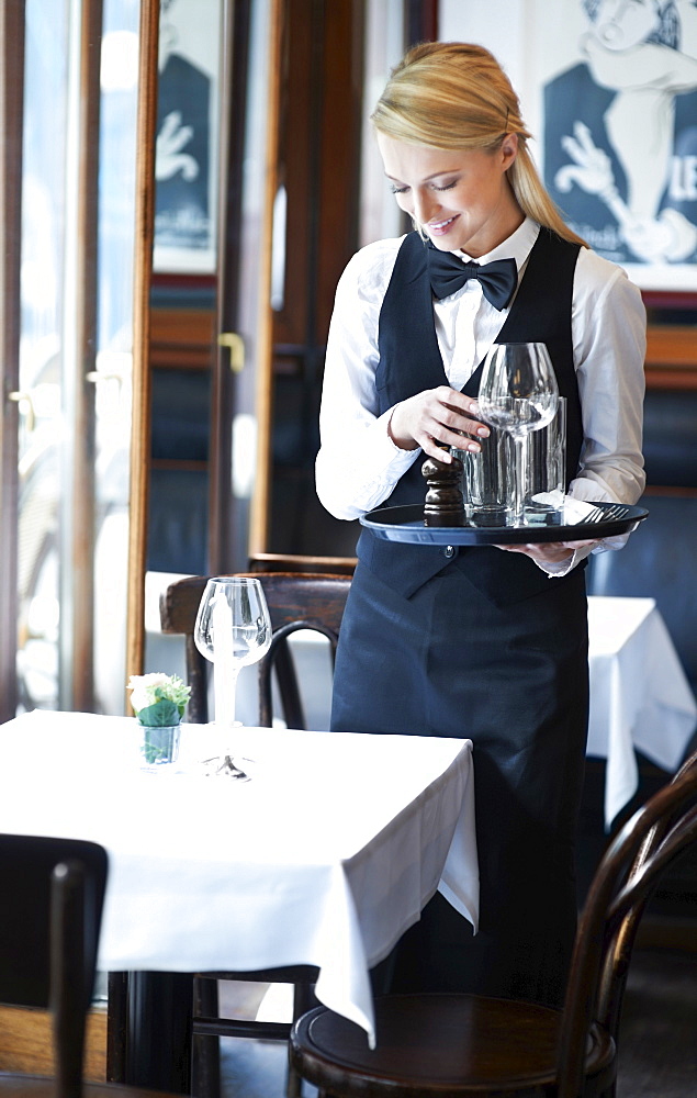 Portrait of young waitress setting table