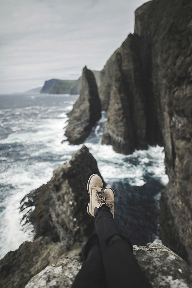 Denmark, Faroe Islands, Sorvagur, Low section of person on sea cliff