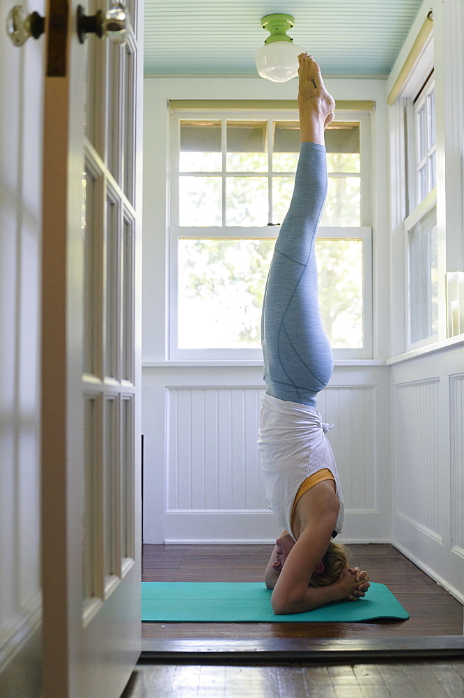 Woman doing headstand on mat