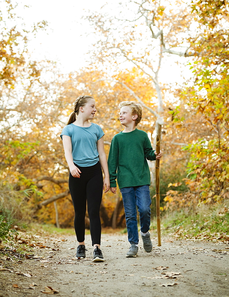 United States, California, Mission Viejo, Boy (10-11) and girl (12-13) walking on footpath in forest