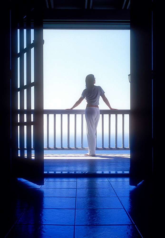 United States, United States Virgin Islands, St. John, Rear view of woman standing on balcony of holiday villa by sea