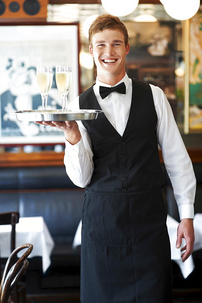 Portrait of waiter holding champagne flutes on tray