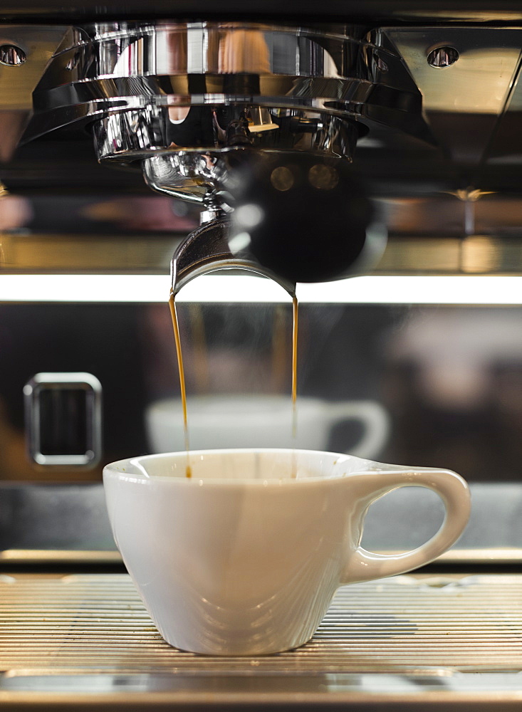 Coffee flowing from coffee machine in coffee shop, close-up