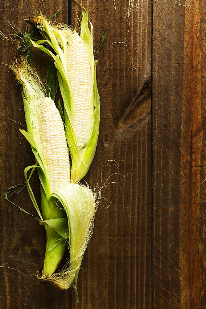 Overhead view of two corn cobs on table