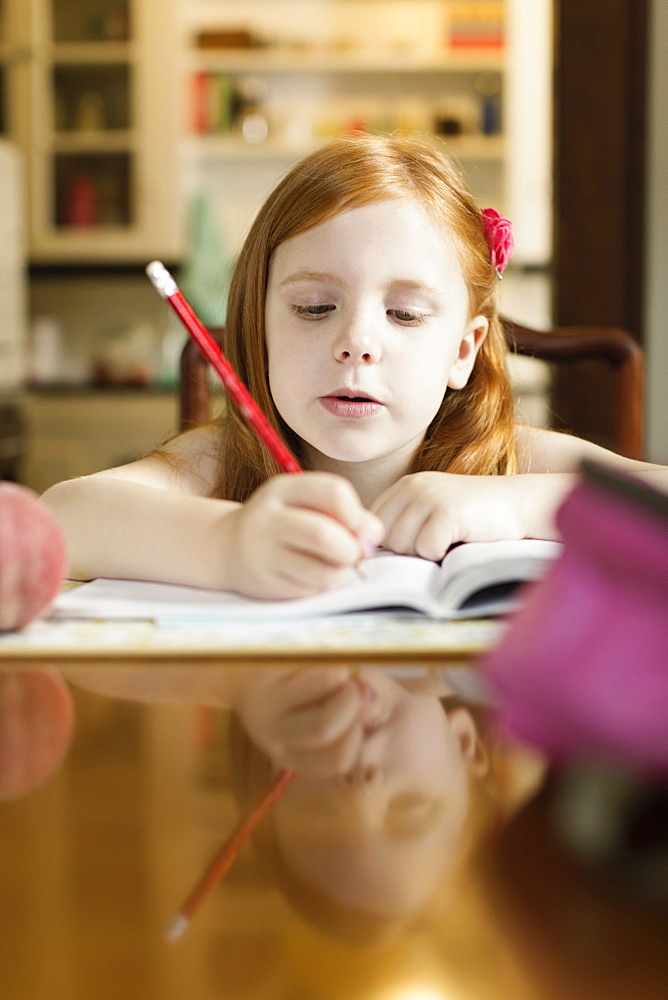 Girl doing school homework at dining room table